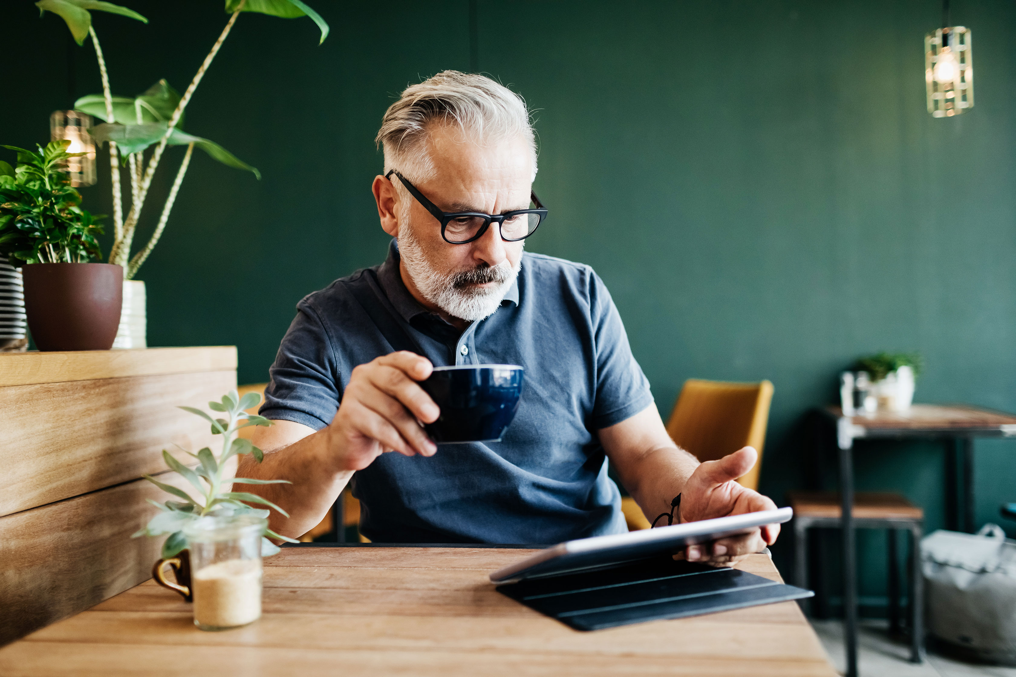 Man_Reading_Tablet_at_Cafe Man_Reading_Tablet_at_Cafe