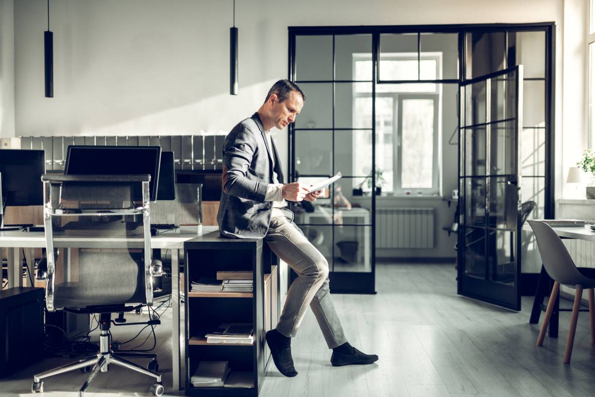 Standing_Businessman_Reading_Document Stylish prosperous businessman reading documents