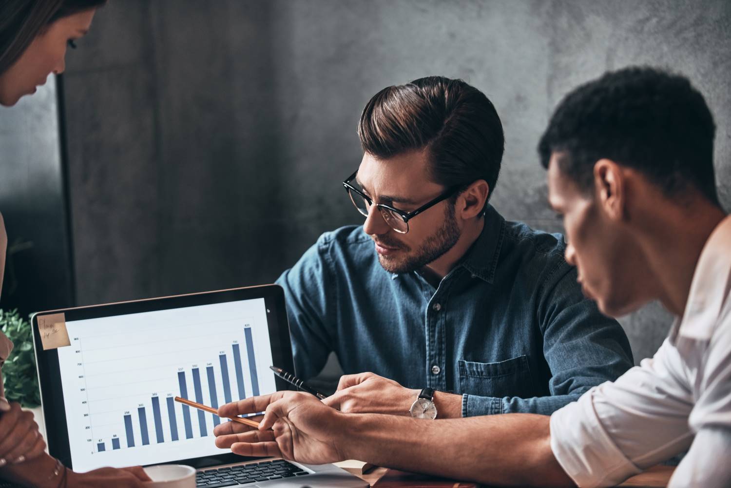Colleagues review bar graph data Young business people analyzing sales
