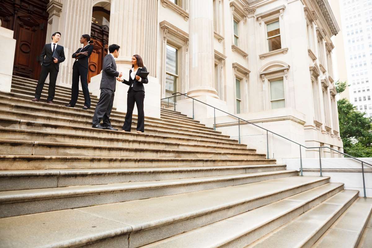 Four professionals talking on steps of a building Four professionals talking on steps of a building