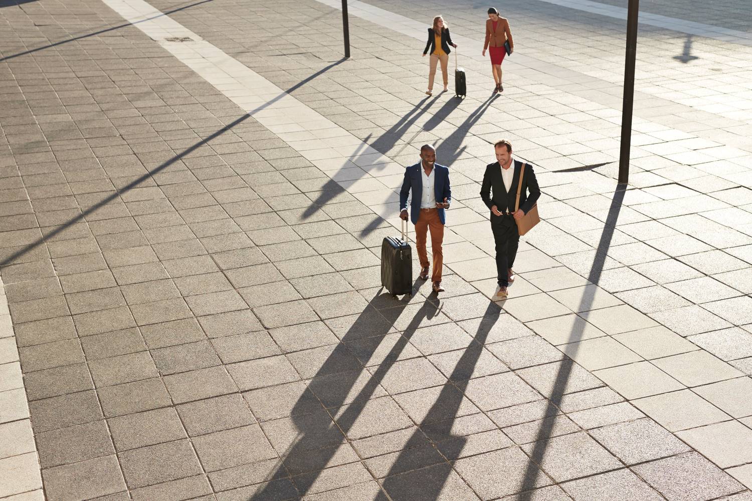 Businesspeople Walking Across Square With Suitcases Businesspeople Walking Across Square With Suitcases
