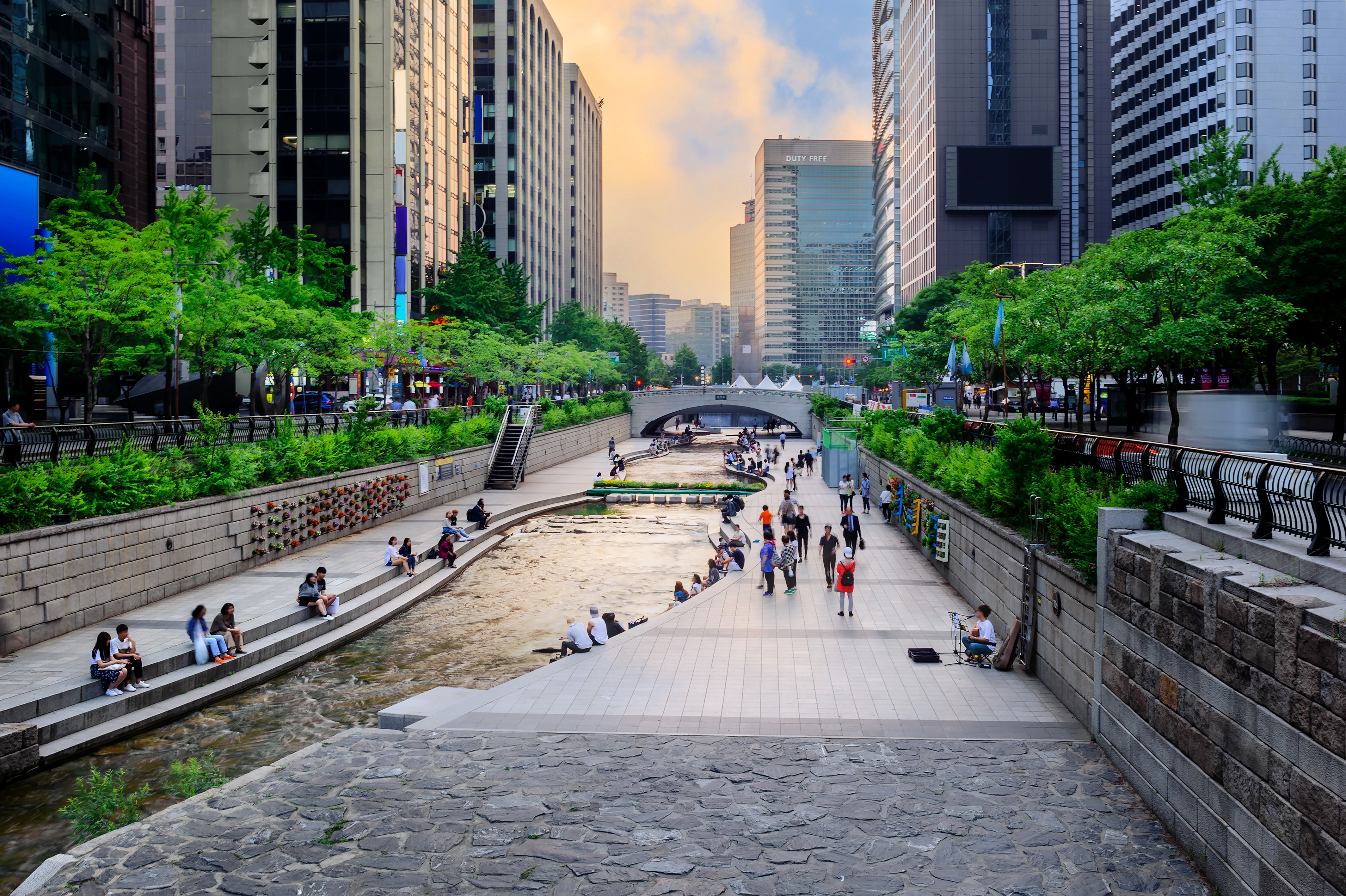City Stream Park With Crowd At Sunset Clouds 